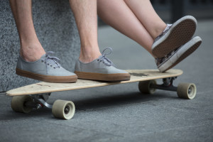 Feet couple of teenagers in sneakers standing on longboard closeup.